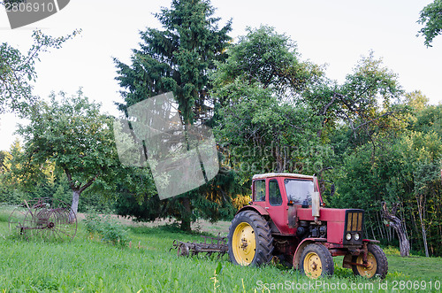 Image of rustic farm tractor in summer garden 