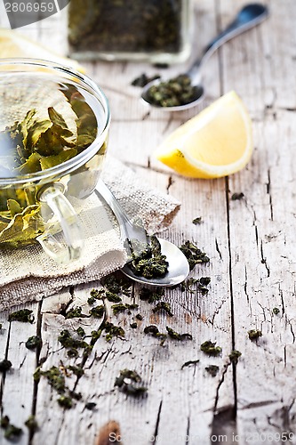 Image of cup of green tea, spoon and lemon 