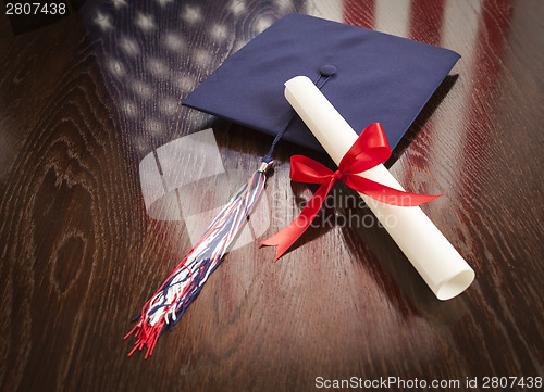 Image of Graduation Cap and Dipoma on Table with American Flag Reflection