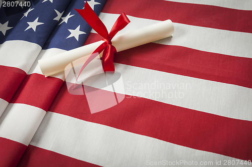 Image of Ribbon Wrapped Diploma Resting on American Flag with Copy Space