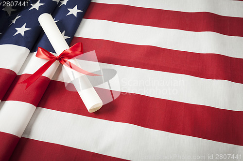 Image of Ribbon Wrapped Diploma Resting on American Flag with Copy Space