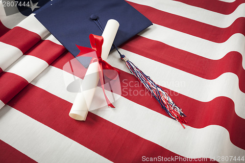 Image of Graduation Cap and Diploma Resting on American Flag