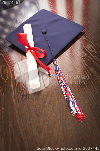 Image of Graduation Cap and Dipoma on Table with American Flag Reflection