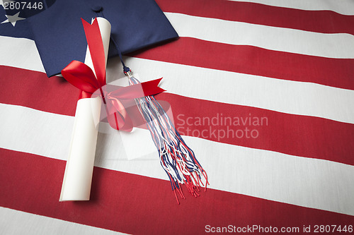 Image of Graduation Cap and Diploma Resting on American Flag