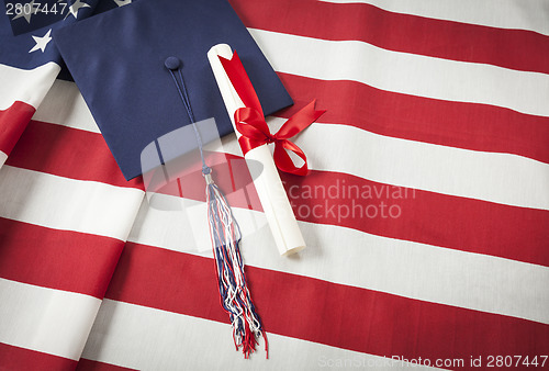 Image of Graduation Cap and Diploma Resting on American Flag