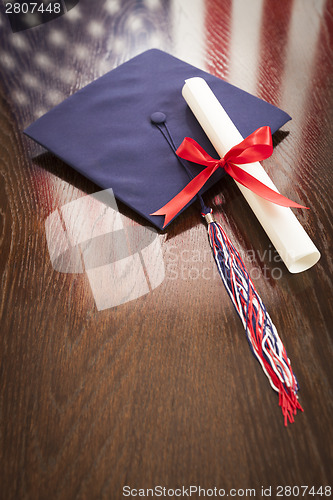 Image of Graduation Cap and Dipoma on Table with American Flag Reflection
