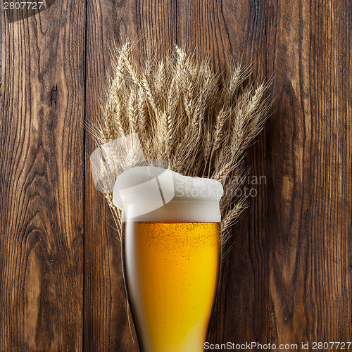 Image of Glass of beer with wheat on wood