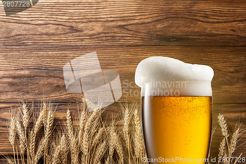 Image of Glass of beer with wheat on wood