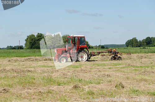Image of tractor ted hay dry grass in agriculture field 