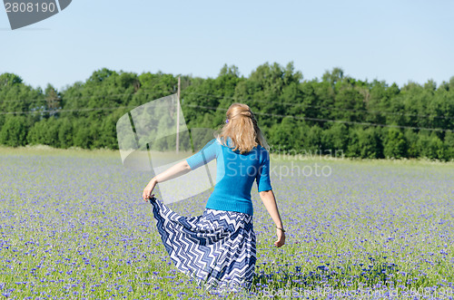 Image of girl with blue skirt dance in cornflower meadow  