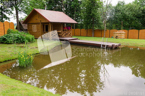 Image of new rural bathhouse and pond with plank footbridge 