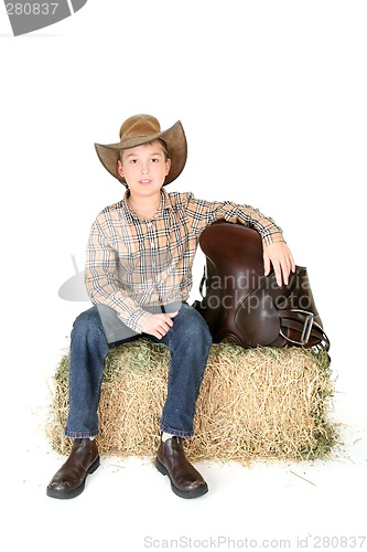 Image of Boy on hay bale with saddle