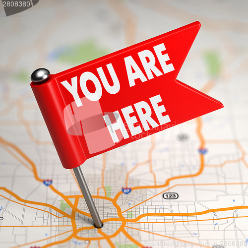 Image of You Are Here - Small Flag on a Map Background.