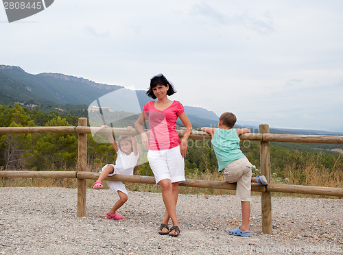 Image of Mother and two children leaning on a fence