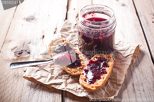 Image of black currant jam in glass jar and crackers