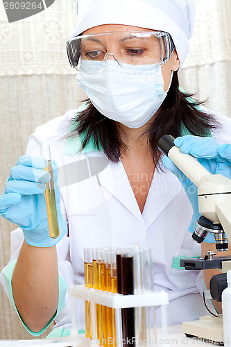 Image of doctor looking at a test tube of yellow solution