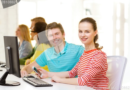 Image of smiling student with smartphone in computer class