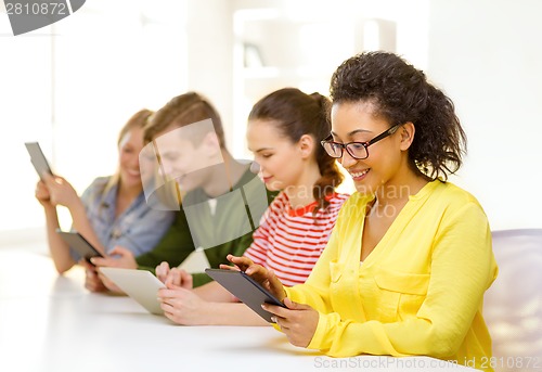 Image of smiling students looking at tablet pc at school