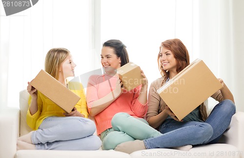 Image of smiling teenage girls with cardboard boxes at home