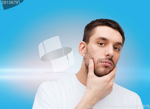 Image of beautiful calm man touching his face