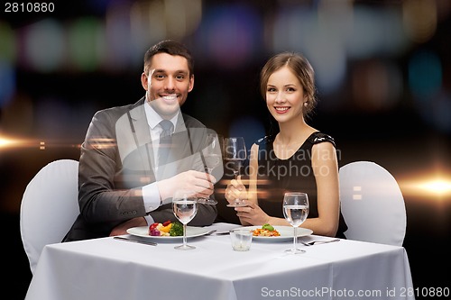 Image of smiling couple eating main course at restaurant