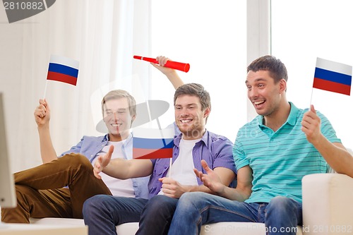 Image of happy male friends with flags and vuvuzela