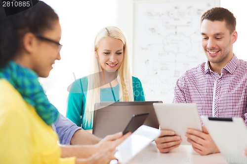 Image of smiling team with table pc and laptop in office