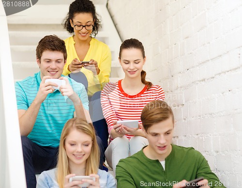 Image of smiling students with smartphone texting at school