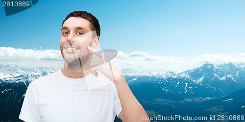 Image of smiling young handsome man pointing to cheek