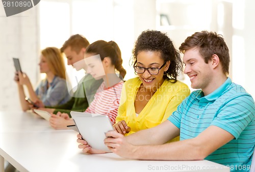 Image of smiling students looking at tablet pc at school