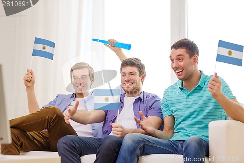 Image of happy male friends with flags and vuvuzela