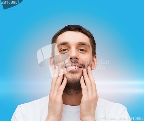 Image of beautiful smiling man touching his face