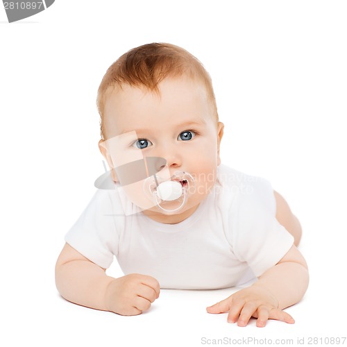 Image of smiling baby lying on floor with dummy in mouth