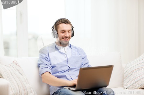 Image of smiling man with laptop and headphones at home