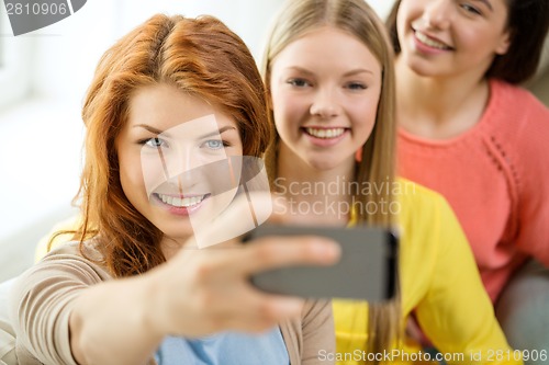 Image of smiling teenage girls with smartphone at home