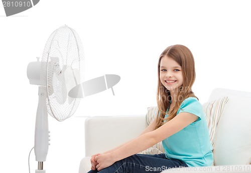 Image of smiling little girl with big fan at home