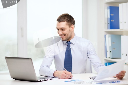 Image of smiling businessman with laptop and documents