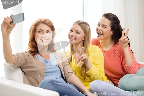 Image of smiling teenage girls with smartphone at home