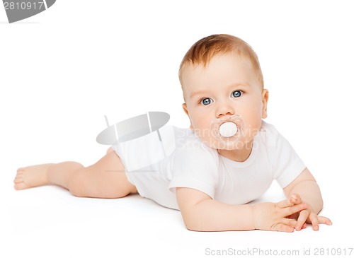 Image of smiling baby lying on floor with dummy in mouth