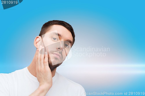 Image of beautiful calm man touching his face