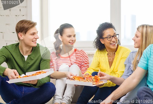 Image of five smiling teenagers eating pizza at home