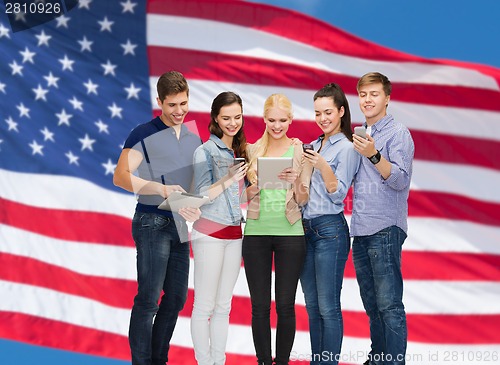 Image of smiling students using smartphones and tablet pc