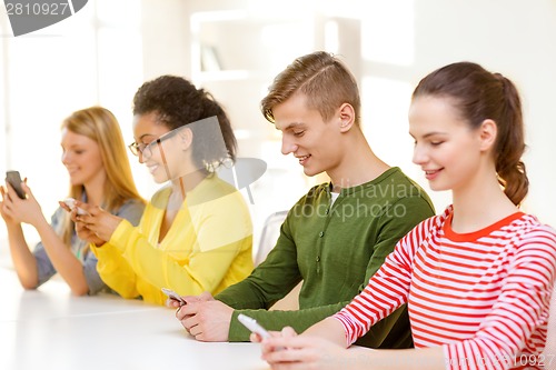 Image of four smiling students with smartphones at school