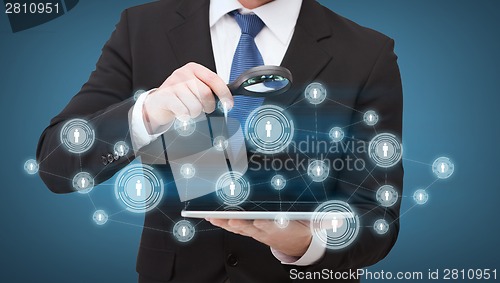 Image of businessman hand holding magnifier over tablet pc