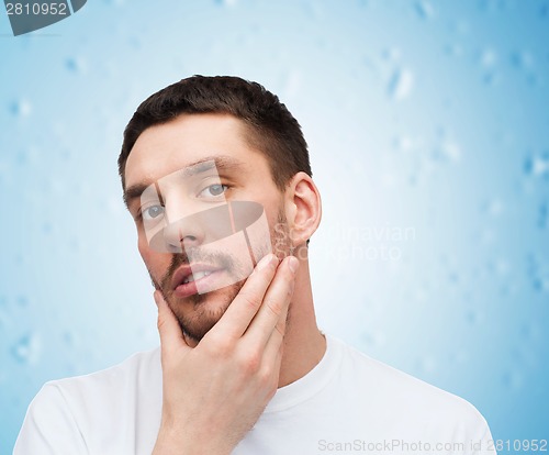 Image of beautiful calm man touching his face