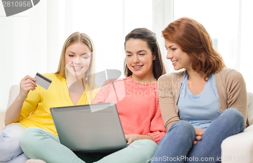 Image of smiling teenage girls with laptop and credit card