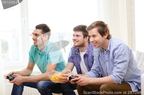 Image of smiling friends playing video games at home