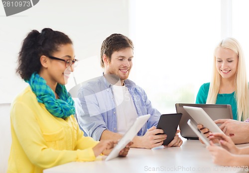 Image of smiling team with table pc and laptop in office