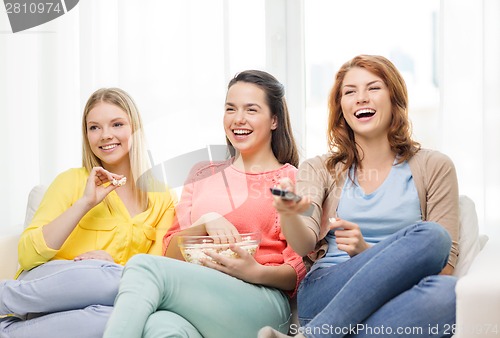 Image of three smiling teenage girl watching tv at home