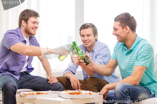 Image of smiling friends with beer and pizza hanging out